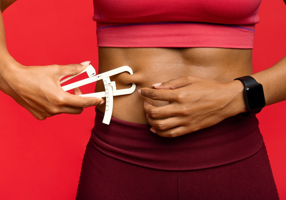 Woman measuring her body fat with body fat caliper